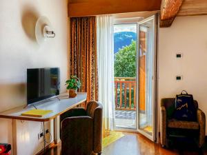 a room with a desk and a window with a balcony at Hotel Los Andes in Castello di Fiemme