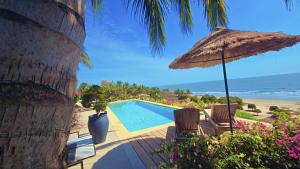 a swimming pool with an umbrella and chairs next to the beach at Villa ALDIANA in Cap Skirring
