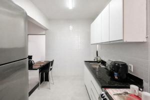 a kitchen with white cabinets and a table in it at Residencial Dois58 in Niterói