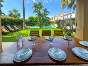 a wooden table with plates and wine glasses on it at Villa Rocamar by Hello Homes Sitges in Sitges