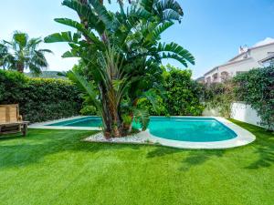 a palm tree next to a swimming pool in a yard at Villa Rocamar by Hello Homes Sitges in Sitges