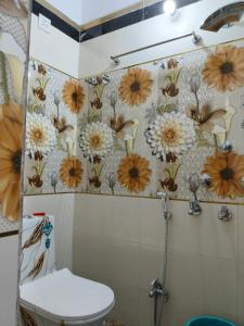 a bathroom with a toilet and flowers on the wall at Rupali Guest House in Patna