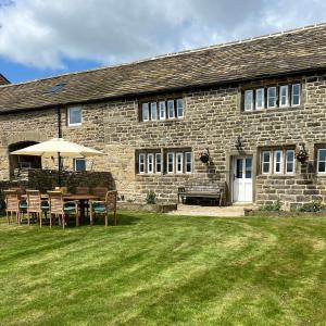 a table with an umbrella in front of a stone building at Moorlands Farm Holidays in Keighley