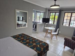 a bedroom with a bed and a kitchen with a table at Fairway Guest Lodge in Margate