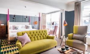 a bedroom with a yellow couch and a bed at The Swan Hotel in Southwold