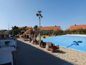 a large swimming pool with chairs and a light pole at Strand en duinen 331 omheinde tuin in Julianadorp