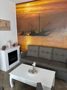 a living room with a couch and a painting of a ship at Pension Appartementhaus Hus Möhlenbarg in Cuxhaven