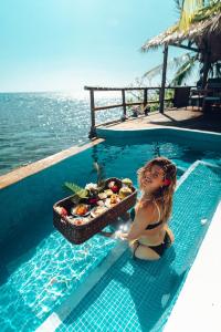 a girl sitting in a swimming pool with a tray of food at Monasterio del Viento in Bahia Maracaibo