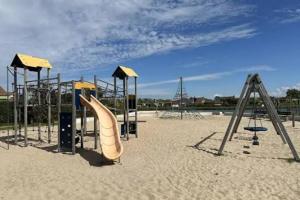 an empty playground with a slide in the sand at Strand en duinen 331 omheinde tuin in Julianadorp