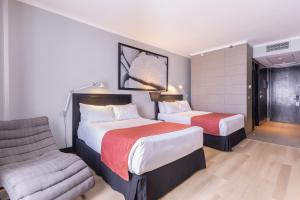 a hotel room with two beds and a chair at Wyndham Santiago Pettra in Santiago
