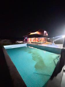 a swimming pool in front of a house at night at BlueSea Villa Kashid beach in Kashid
