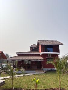 a red house with palm trees in front of it at BlueSea Villa Kashid beach in Kashid