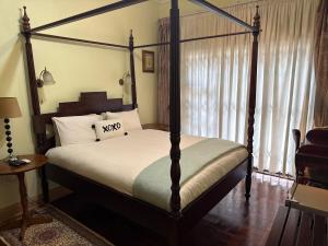 a bedroom with a four poster bed and a window at 45 on Mendelssohn in Johannesburg
