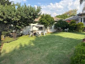 a lawn with a table and chairs in a yard at 45 on Mendelssohn in Johannesburg +2 photos