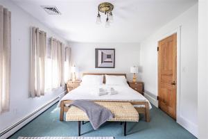 a white bedroom with a bed and a window at Mystic Landing in Kennebunk