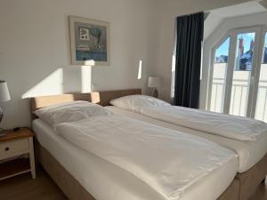 two white beds in a bedroom with a window at Appartementhaus Hoppe in Sylt