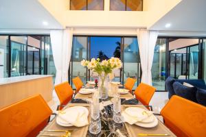 a dining room with a long table and orange chairs at Yuan Villa VIP in Rawai Beach