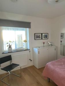 a bedroom with a bed and a chair and a window at Nära strand och hav in Halmstad