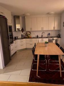 a kitchen with a wooden table and a refrigerator at Nära strand och hav in Halmstad