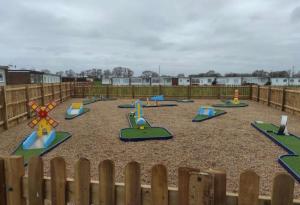 a playground with colorful play equipment in a fence at Norfolk Beach Chalet - California Sands Resort in Great Yarmouth