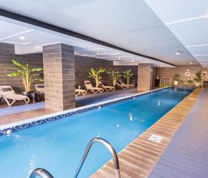 a large swimming pool in a hotel with tables and chairs at Wyndham Santiago Pettra in Santiago