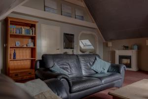 a living room with a leather couch and a fireplace at Achterom in Biggekerke