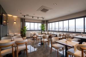 a restaurant with tables and chairs and large windows at Kucuk Velic Hotel in Gaziantep