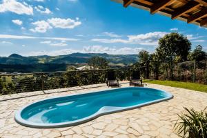 a swimming pool with two chairs and a view of the mountains at Chalé 1 Refúgio do Sol Piscina com Vista para Montanas in Socorro