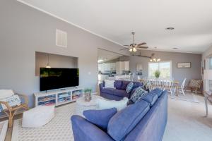 a living room with a blue couch and a tv at Dock Holiday OBX Village in Duck