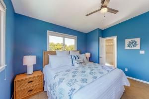 a blue bedroom with a bed and a window at Dock Holiday OBX Village in Duck +39 photos