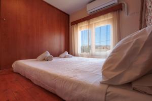 a bedroom with a large white bed with a window at Villa Geomare in Apolakkiá