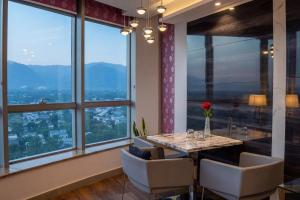 a dining room with a table and chairs and large windows at Walk-Inn Centaurus Hotel Apartments Islamabad in Islamabad