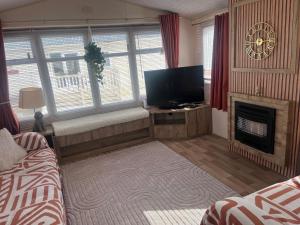 a living room with a television and a fireplace at ellies caravan hire 8 berth in Kinmel Bay +4 photos