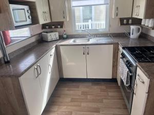 a kitchen with white cabinets and a sink and a stove at ellies caravan hire 8 berth in Kinmel Bay