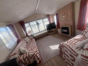 a living room with two beds and a television at ellies caravan hire 8 berth in Kinmel Bay