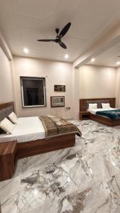 a bedroom with two beds and a flat screen tv at Hotel Tara Grand in Mathura