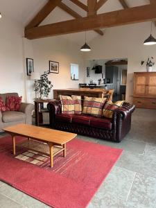 a living room with a leather couch and a coffee table at Moorlands Farm Holidays in Keighley