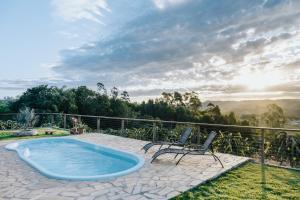 a hot tub on a patio with two chairs at Chalé 1 Refúgio do Sol Piscina com Vista para Montanas in Socorro