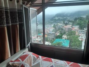 a bedroom with a view of a city from a window at Rahul Residency Homestay- Couple & Family friendly- 'prime location- Easy access to Mall Rd- WiFi- Smart TV - Kitchen- City view in Solan