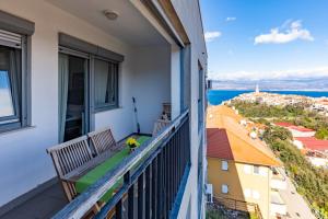 a balcony with a bench and a view of the city at Apartman Dokić 3 in Vrbnik