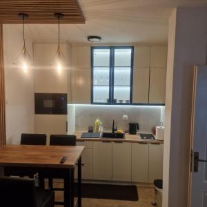 a kitchen with white cabinets and a table and a window at Apartman Ana Bijeljina in Bijeljina +3 photos