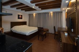 a bedroom with a bed and a table and a kitchen at Fizzy Stay in Jawlakhel