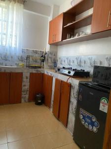 a kitchen with a black refrigerator and wooden cabinets at Esskayhomestays in Eldoret