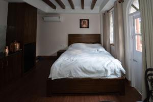 a bedroom with a bed with white sheets and a window at Fizzy Stay in Jawlakhel