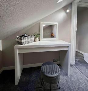 a white console table with a mirror and a stool at The TEVIOT in the centre of Melrose in Melrose