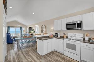 a kitchen with white cabinets and a dining room at Perched on the Dune In the Heart of Surf City in Surf City