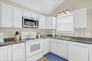 a kitchen with white cabinets and a stove top oven at Perched on the Dune In the Heart of Surf City in Surf City