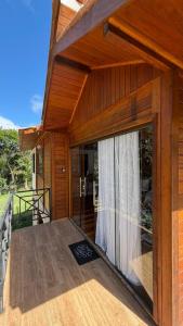 a wooden house with a large glass door on a deck at Chalé Garden - Pedra Azul in Domingos Martins