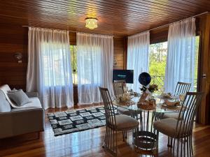 a dining room with a table and a couch at Chalé Garden - Pedra Azul in Domingos Martins
