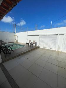 a patio with a table and chairs and a pool at Star HOUSE beach in Aracaju
